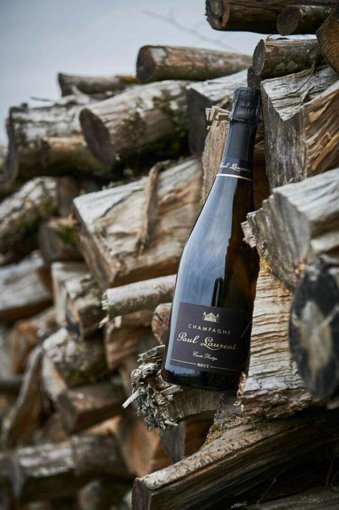 Bottle of Cuvée Prestige Brut resting on stacked firewood